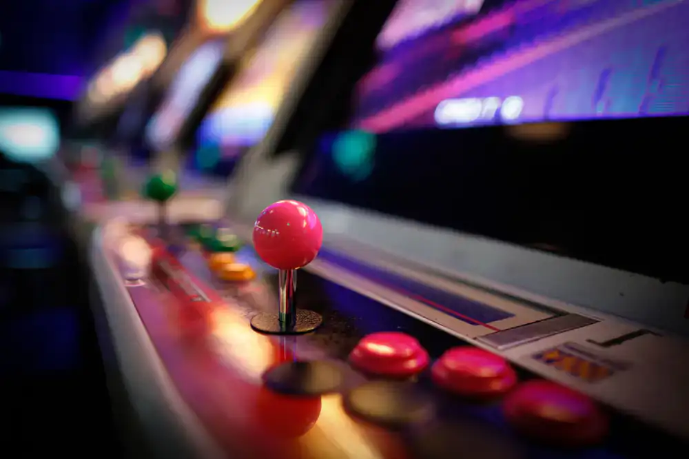 Row of classic retro arcade cabinets glowing in the dark